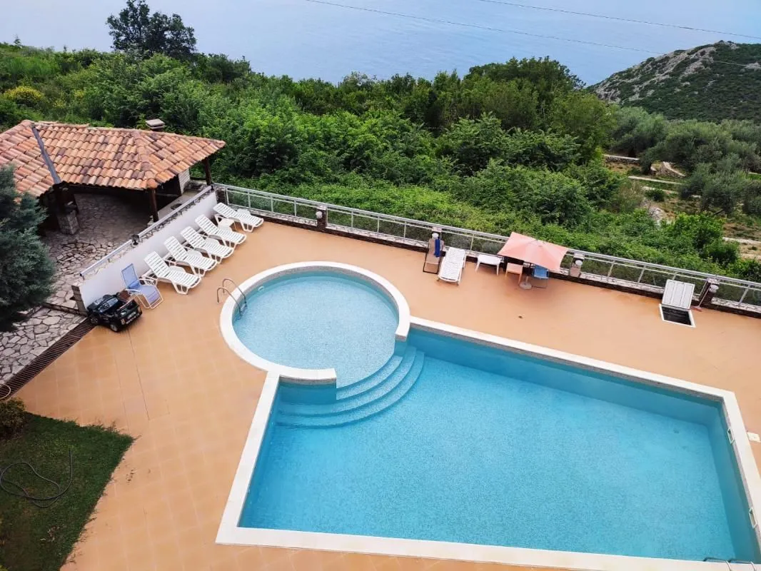 Outdoor area with a swimming pool, sun loungers, and a sea view.