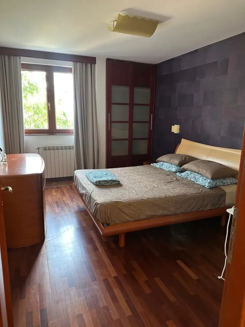 Furnished bedroom with a double bed, wardrobe, and window.