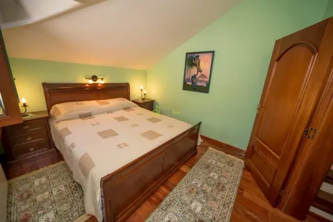 Bedroom with a double bed, wooden furniture, and sloping ceiling. - image 5