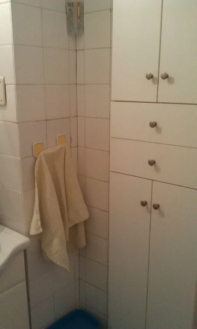 Part of a bathroom featuring a white built-in cabinet and a hanging towel.