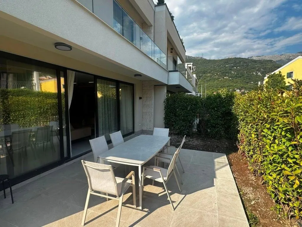Terrace with outdoor furniture in front of a modern building with a green view.