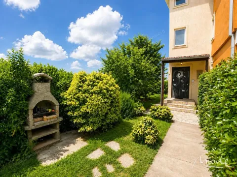 Green yard with a barbecue and a pathway leading to the entrance of the house. - image 3