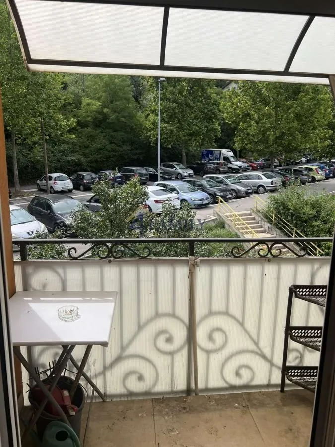 Manji namešteni balkon sa pogledom na parking i zelenilo.