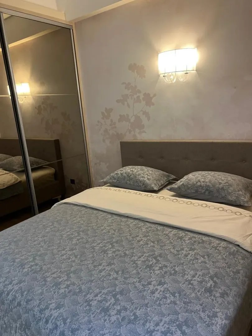 Uređena spavaća soba sa bračnim krevetom i ugradnim plakarom.