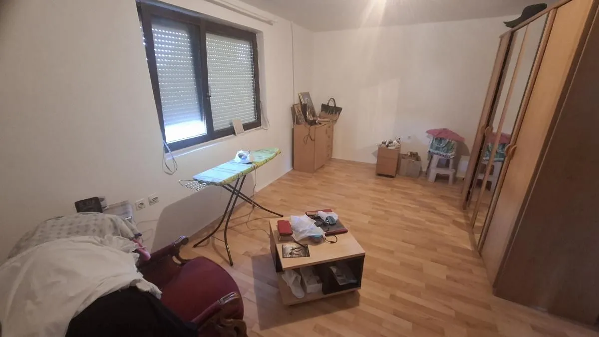 Manja soba sa garderoberom, krevetom i daskom za peglanje.