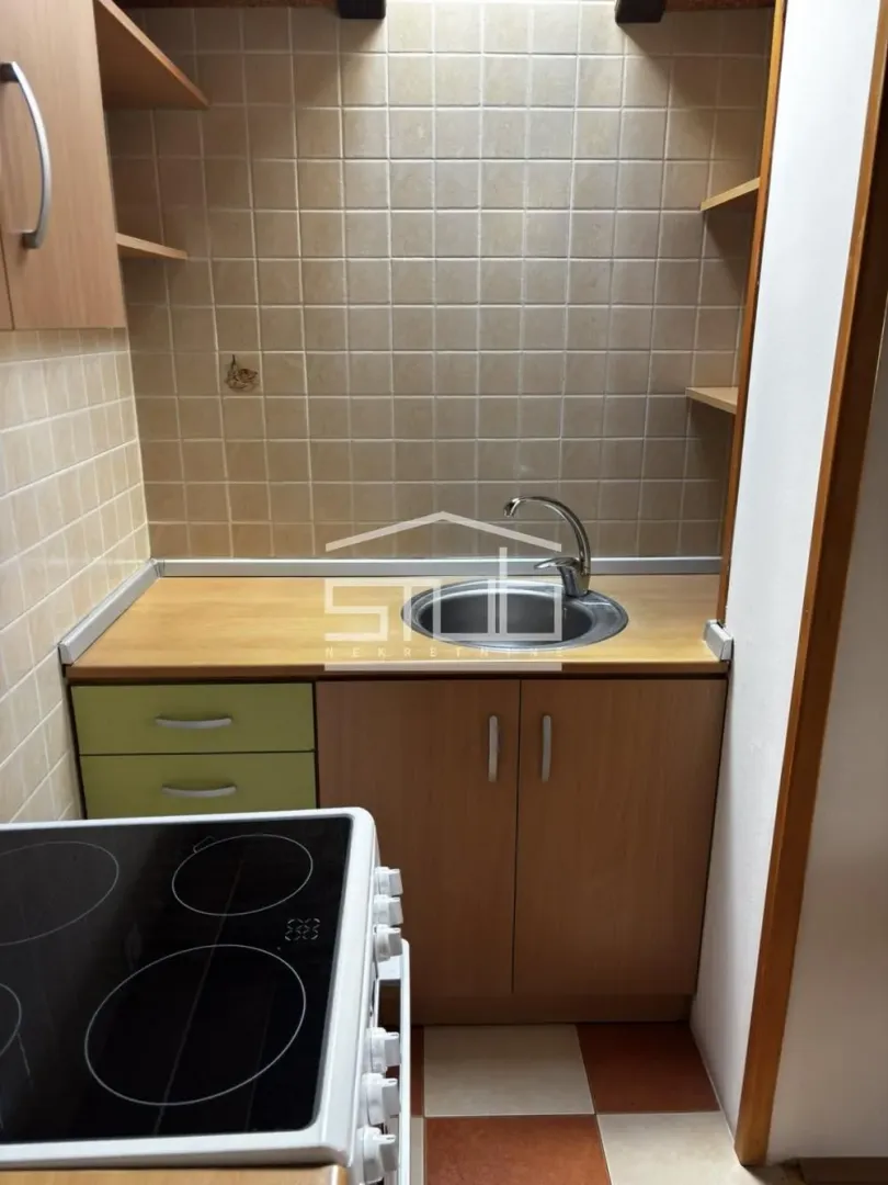 Manja kuhinja sa sudoperom, radnom površinom i šporetom.