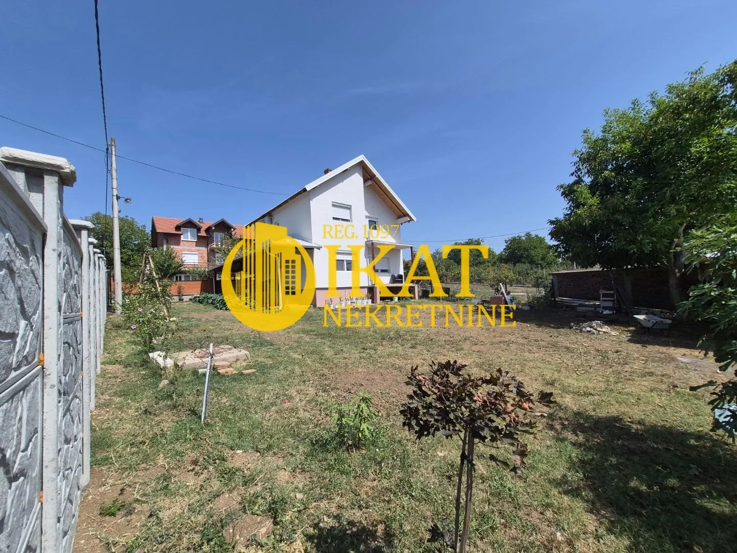 Pogled na dvorište i fasadu porodične kuće sa okućnicom.