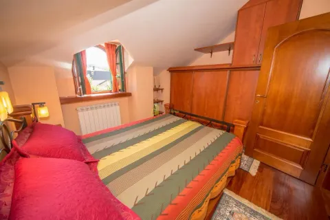 Furnished bedroom with a double bed, wooden wardrobes, and a sloped ceiling. - image 25