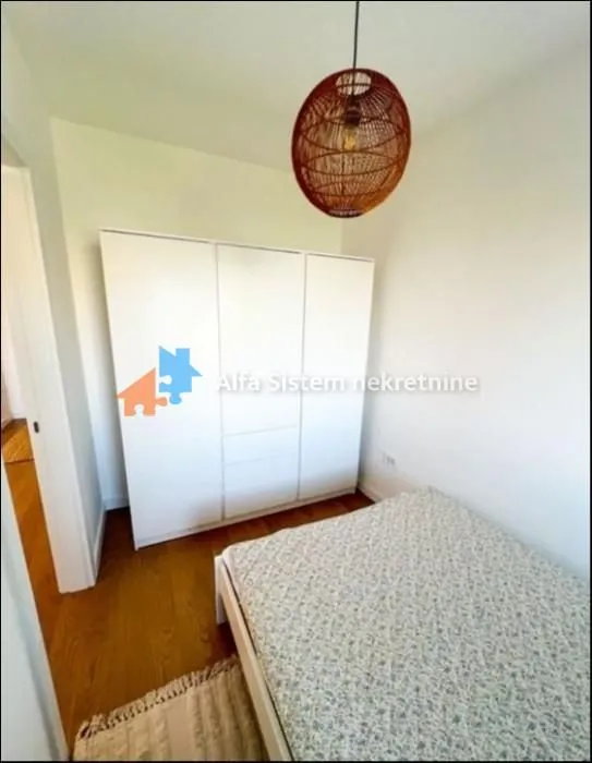 Manja spavaća soba sa krevetom i belim garderoberom.