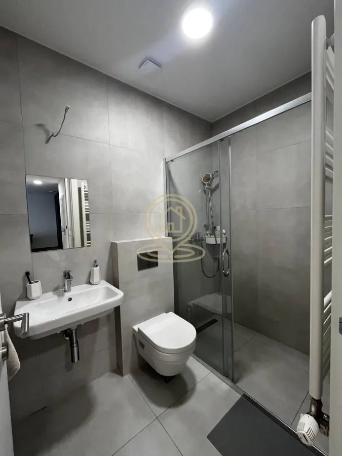 Moderno kupatilo sa tuš kabinom, umivaonikom i wc šoljom.