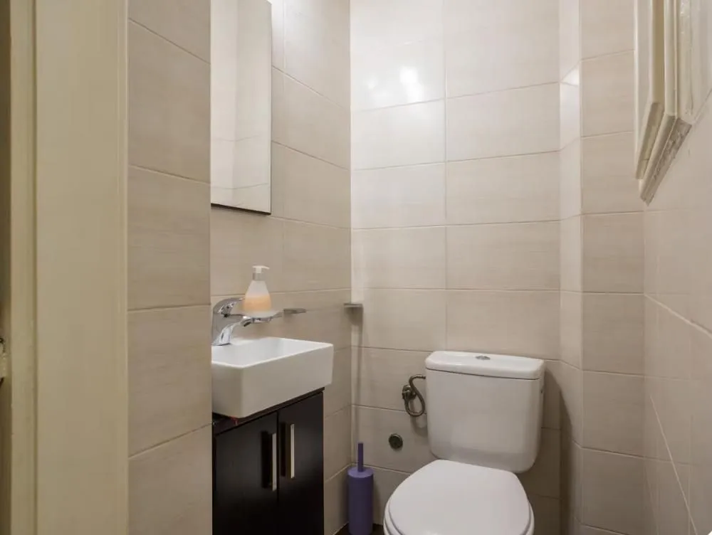 Smaller tiled bathroom with a sink and a toilet.
