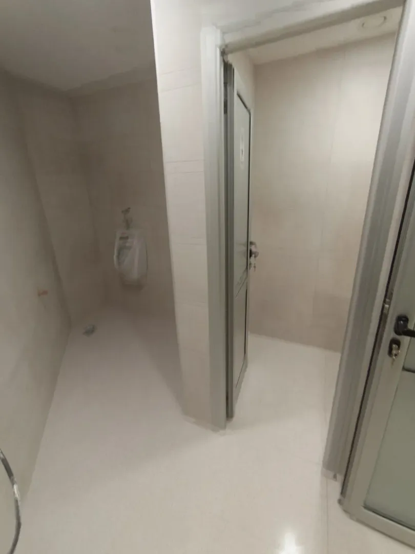 A simple tiled restroom with a urinal and partitions.