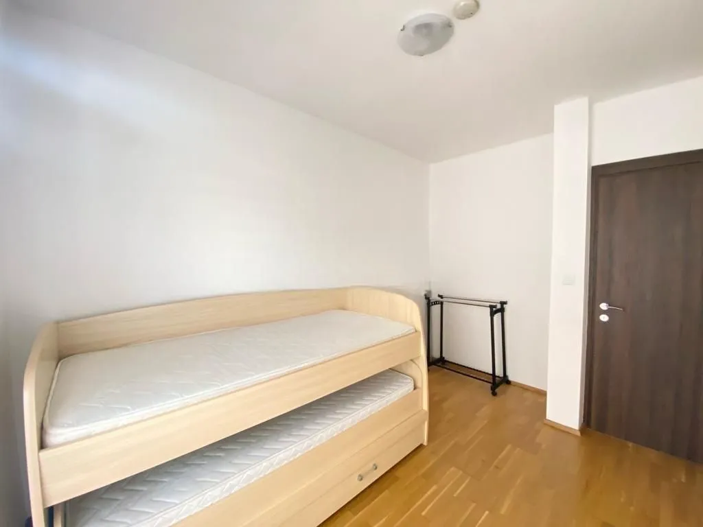 Small bedroom with a pull-out bed and wooden flooring.