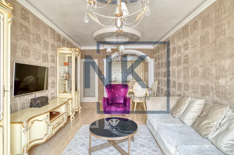 Living room with a sofa, TV, and dining area in the background.