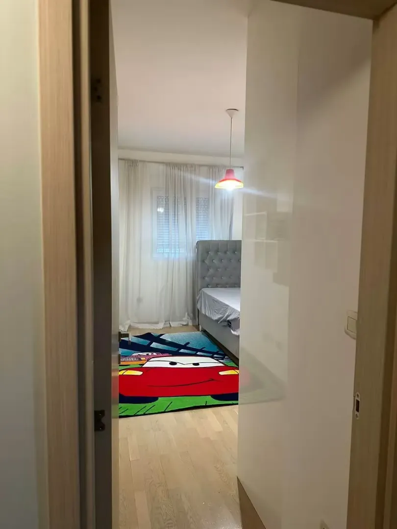 Pogled iz hodnika u dječiju spavaću sobu sa krevetom i tepihom.