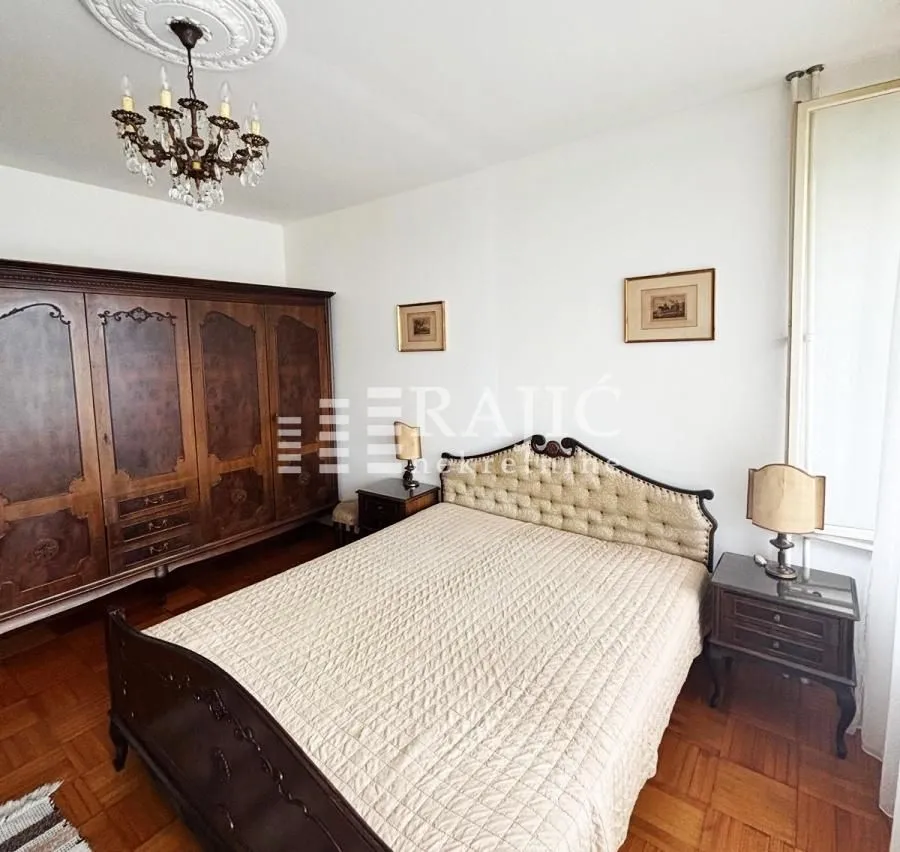 Furnished bedroom with a large double bed and a wooden wardrobe.