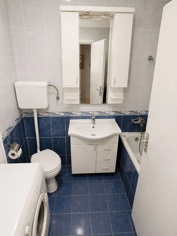 Kupatilo sa kadom, umivaonikom, WC šoljom i belim elementima sa ogledalom.