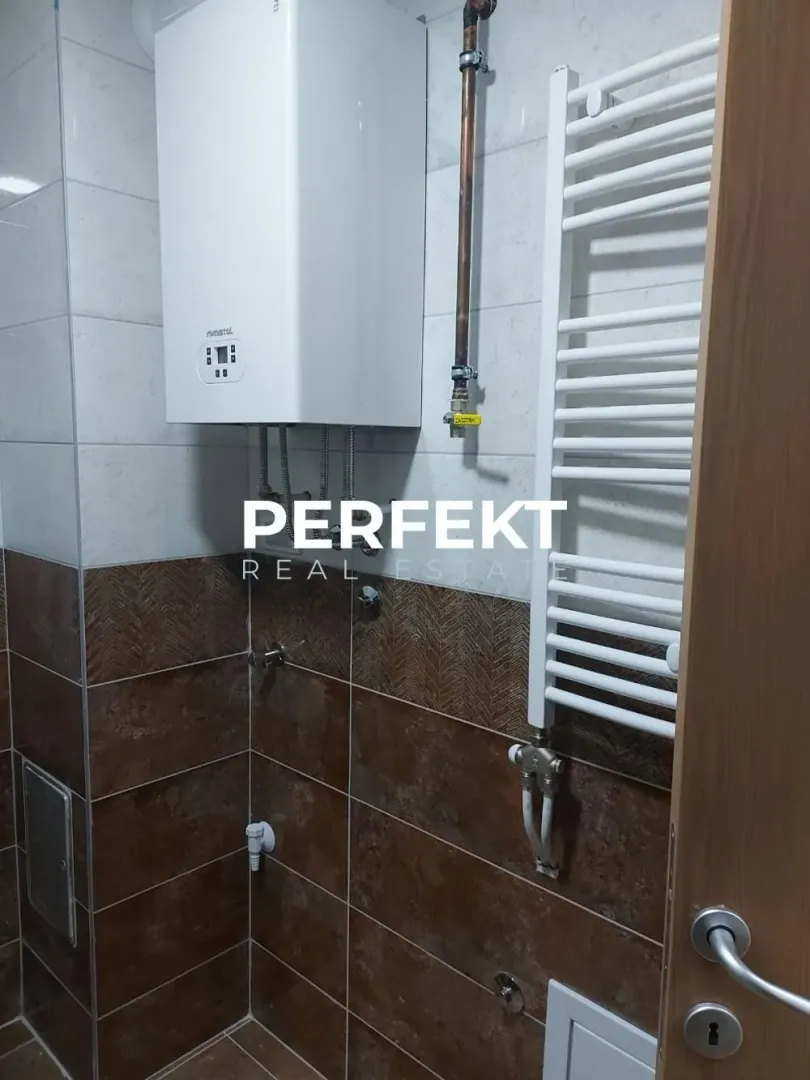 Bathroom with tiles, water heater, and a towel radiator.
