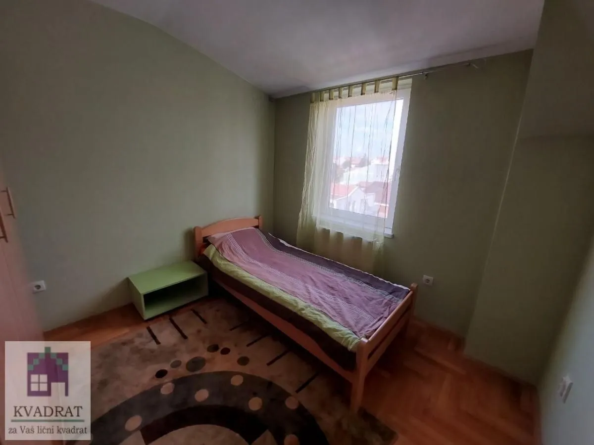 Bedroom with a single bed, window, and hardwood flooring.
