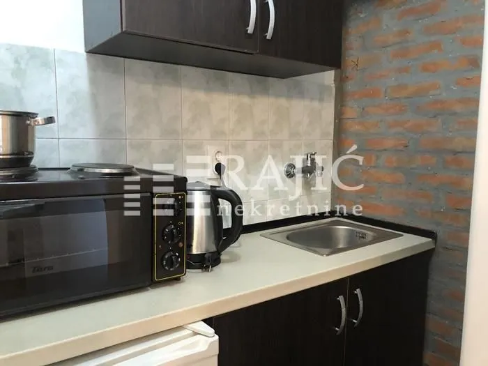 Small kitchen with a sink, stove, and exposed brick wall.