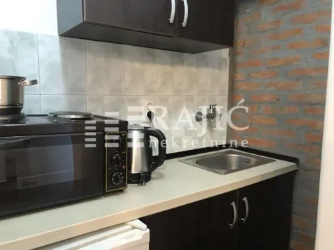 Small kitchen with a sink, stove, and exposed brick wall. - image 7