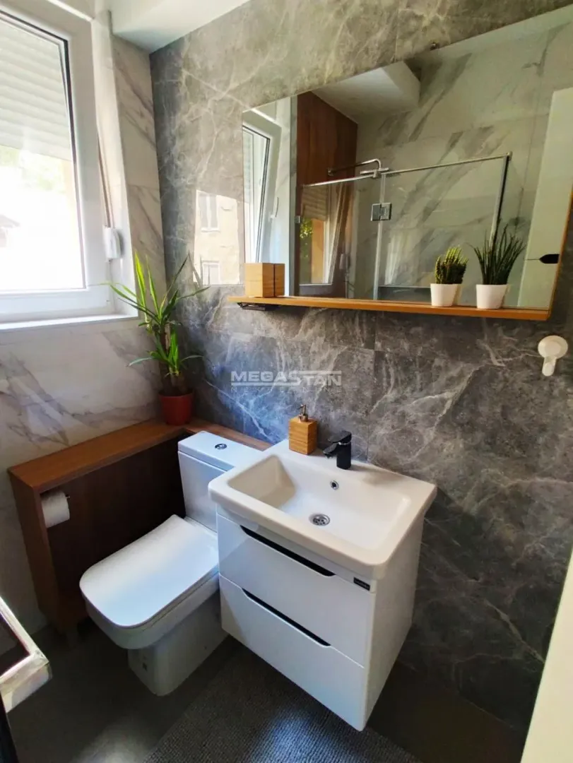 Modernly equipped bathroom with a washbasin, toilet, and mirror.