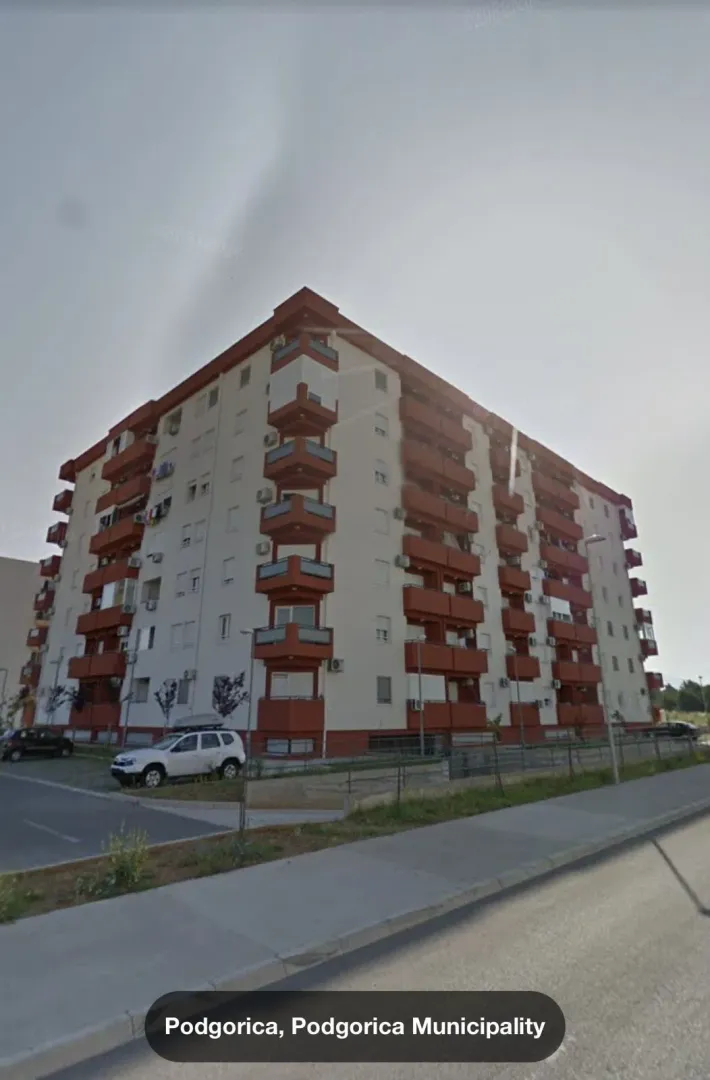 Eksterijer višespratne stambene zgrade sa crvenim i bijelim detaljima.