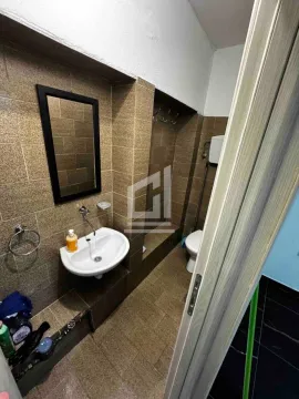 Small bathroom with a sink, mirror, and toilet, tiled in brown. - image 3