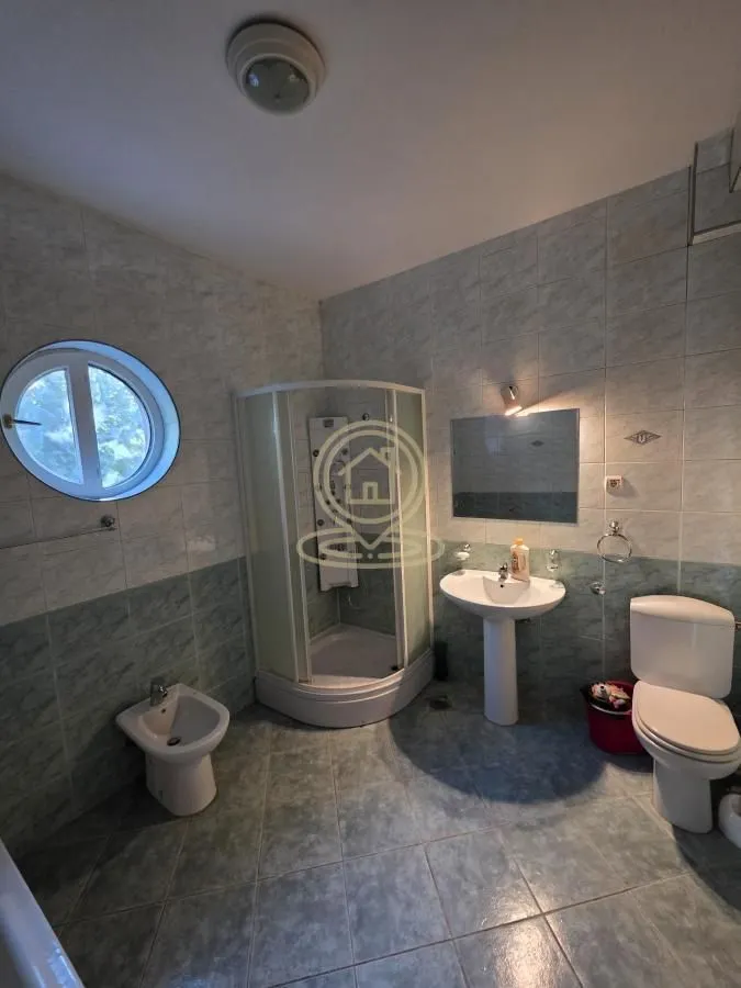 Bathroom equipped with a shower cabin, washbasin, toilet bowl, bidet, and a round window.