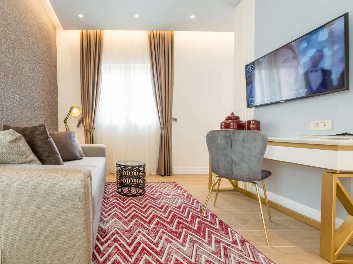 Bright living room with a modern sofa, a writing desk, and a wall-mounted TV.