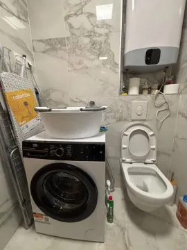 Bathroom equipped with a toilet, washing machine, and water heater. - image 7