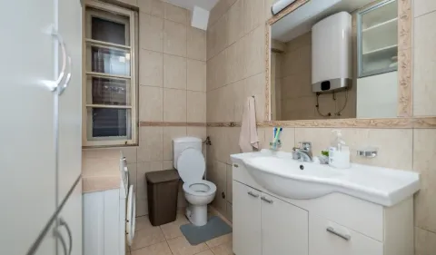 Bathroom with a sink, toilet, water heater and a window. - image 9