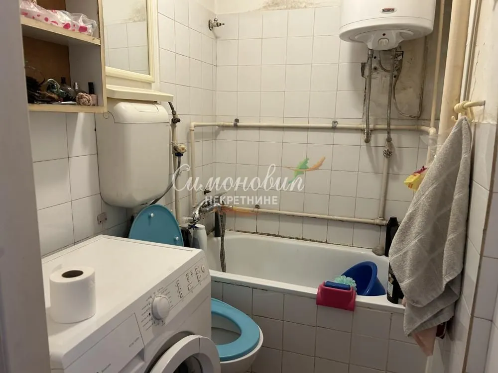 Starije kupatilo sa kadom, WC šoljom i veš mašinom.