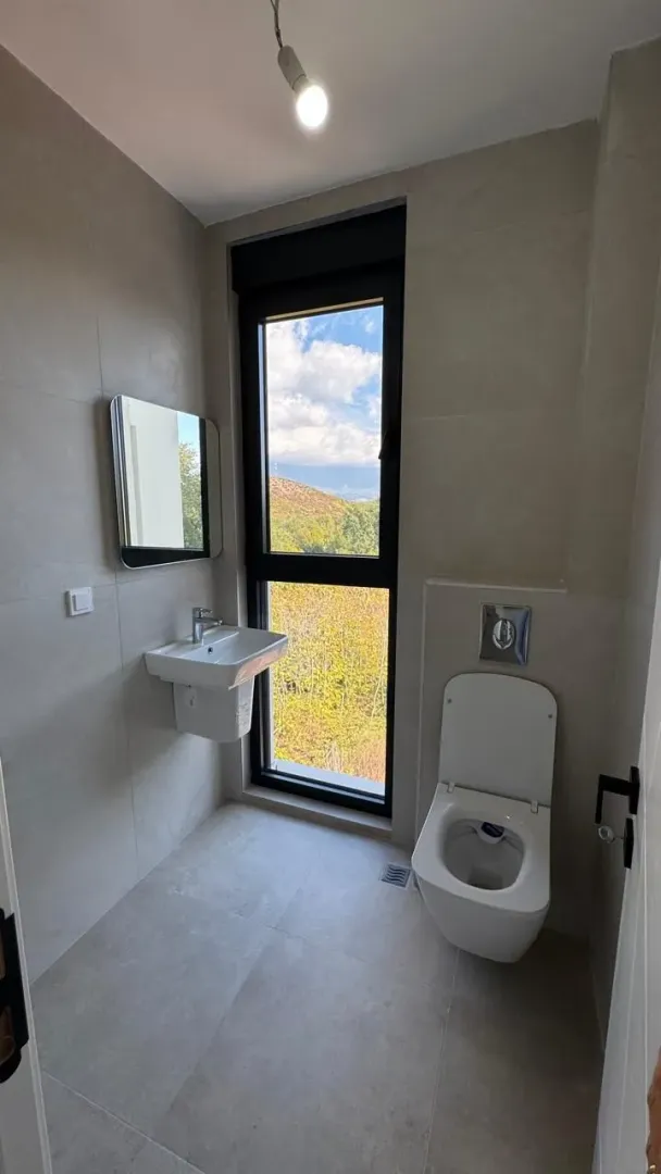 Moderno opremljeno kupatilo sa prozorom i pogledom na prirodu.
