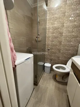 Smaller bathroom with a shower cabin, toilet, washbasin, and washing machine. - image 11