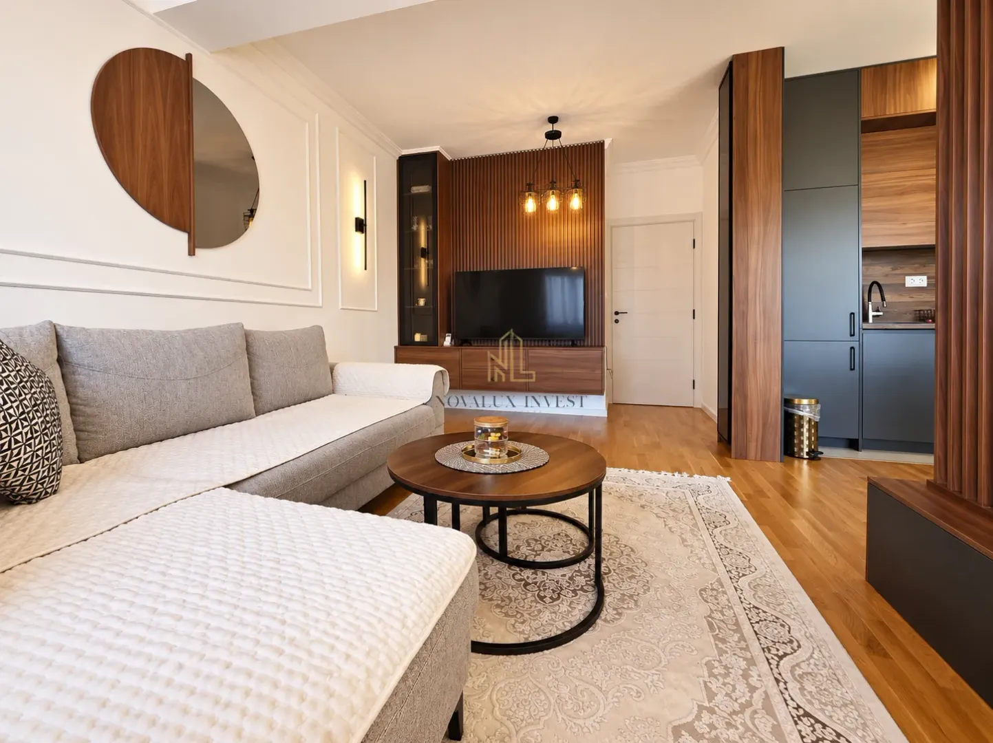 Living room with a sofa, coffee table and TV, connected to the kitchen.