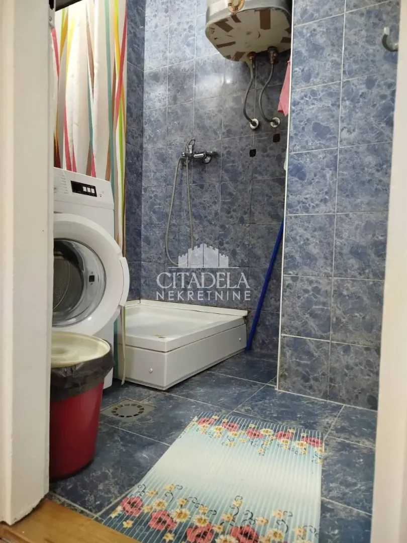 Tiled bathroom with a shower cabin and a washing machine.