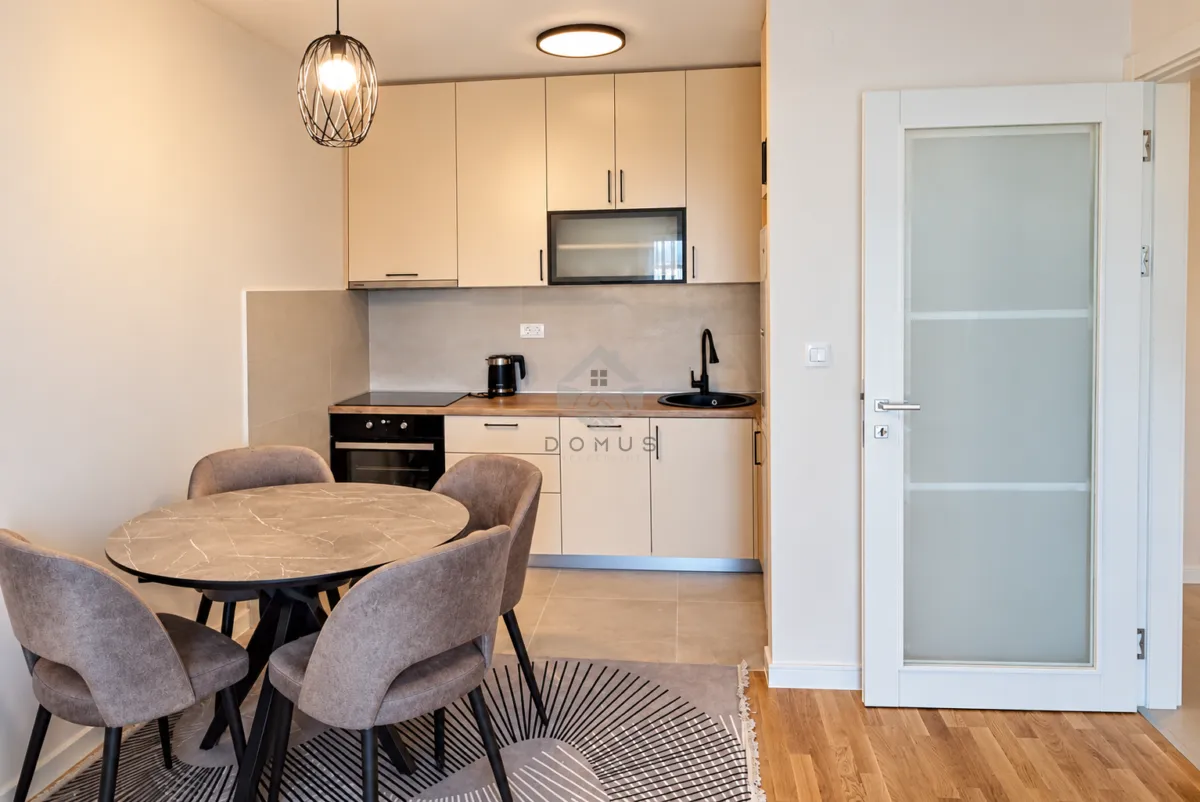 Kitchen with dining area equipped with light-colored cabinets and a round dining table with chairs.