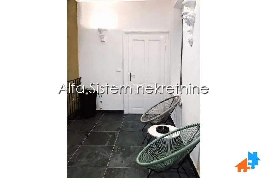 Natkrivena terasa sa keramičkim pločicama i garniturom za sedenje.