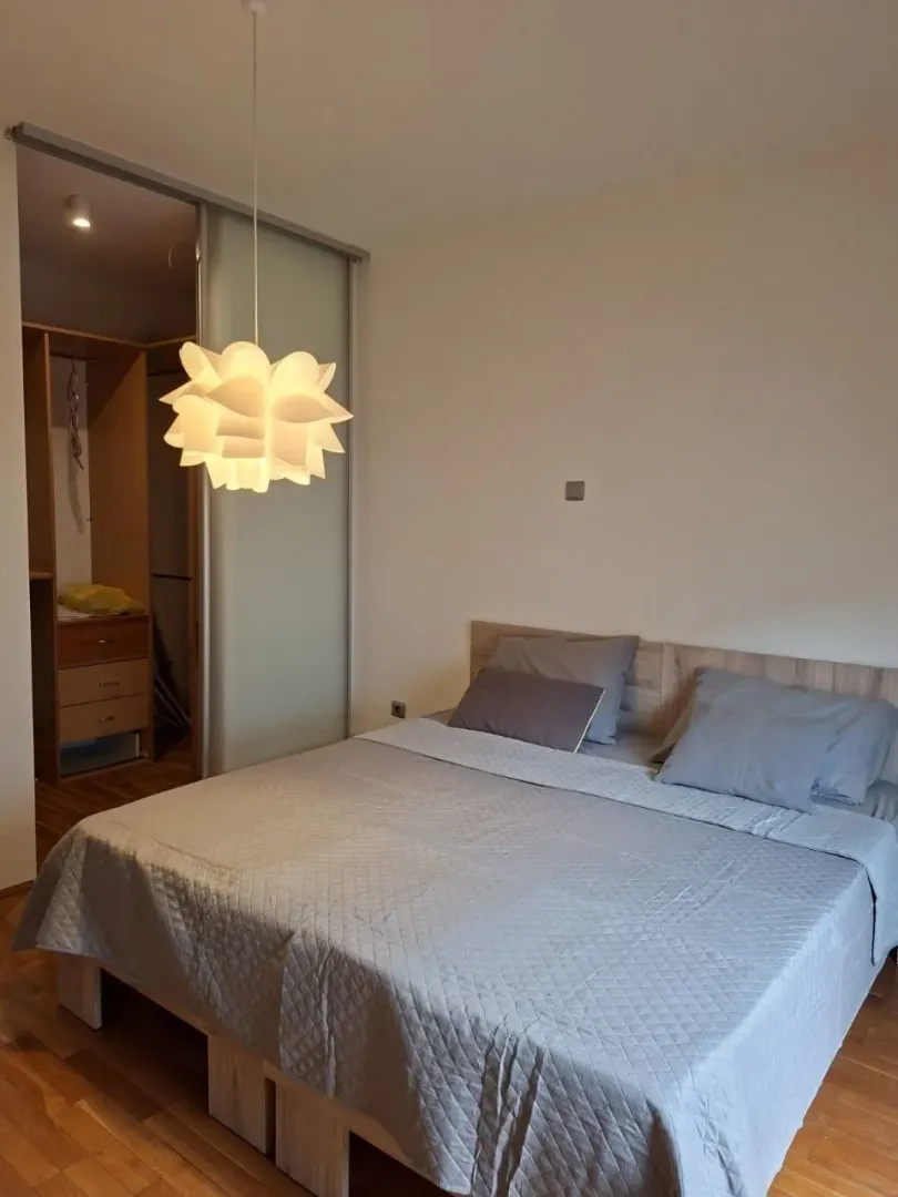 Furnished bedroom with a double bed and a walk-in wardrobe in the background.