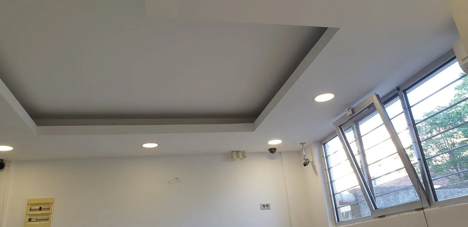 Empty room with a suspended ceiling and recessed lighting.
