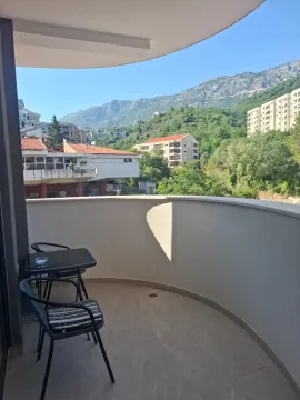 Semi-circular balcony with a table, two chairs, and a view of the surroundings and hills. - image 5