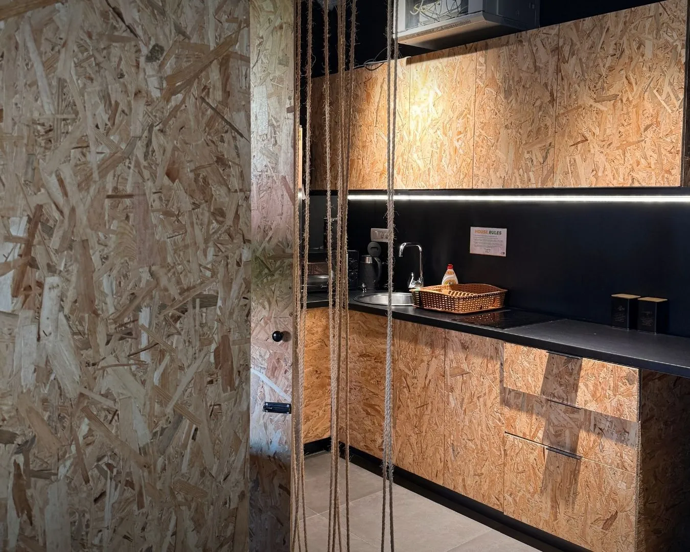 Modern kitchen with OSB board cabinets and a black countertop.
