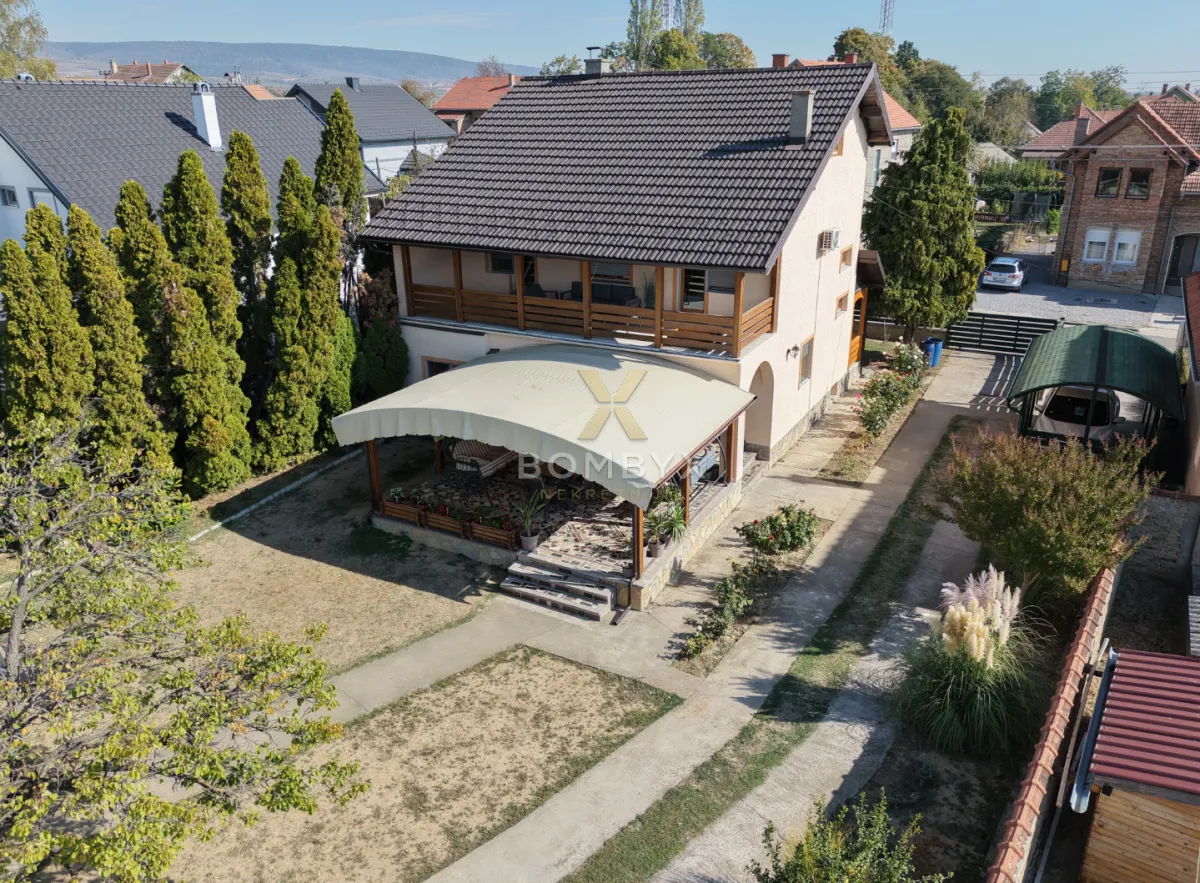 Pogled iz vazduha na dvorište kuće sa terasom i uređenim zelenilom.