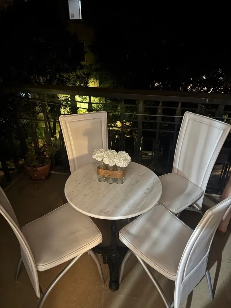 Furnished terrace with a small dining table and chairs at night.