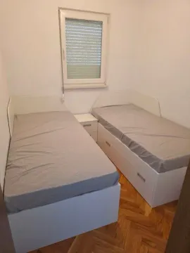Manja spavaća soba sa dva singl kreveta i prozorom. - image 6
