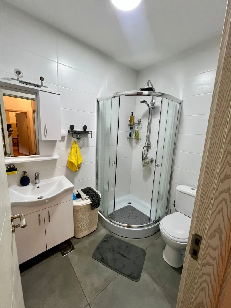 Smaller bathroom with a shower cabin, washbasin, and toilet.