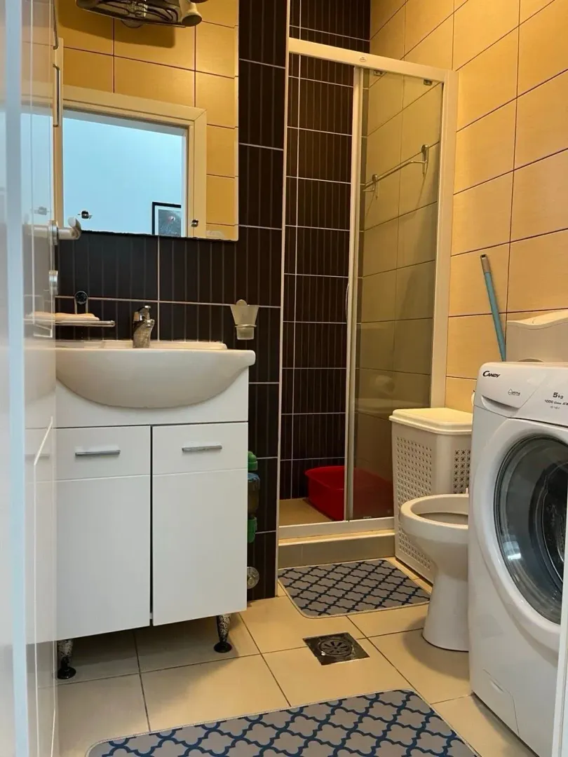 Manje kupatilo sa tuš kabinom, umivaonikom i veš mašinom.