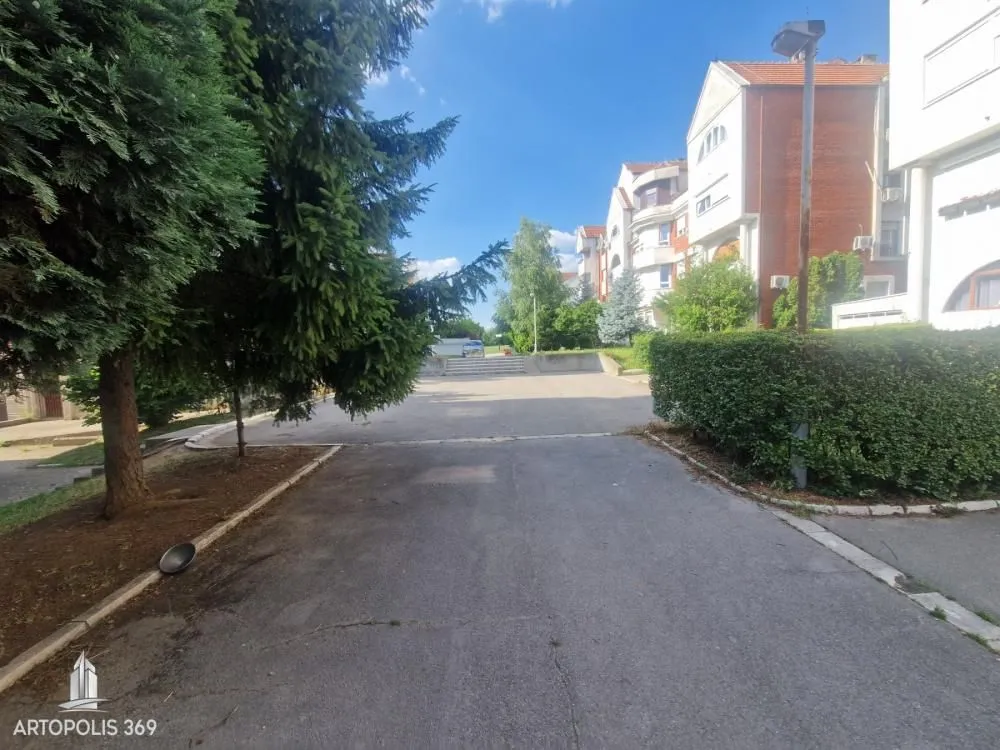 Pogled na dvorište i prilaz zgradi sa zelenilom.