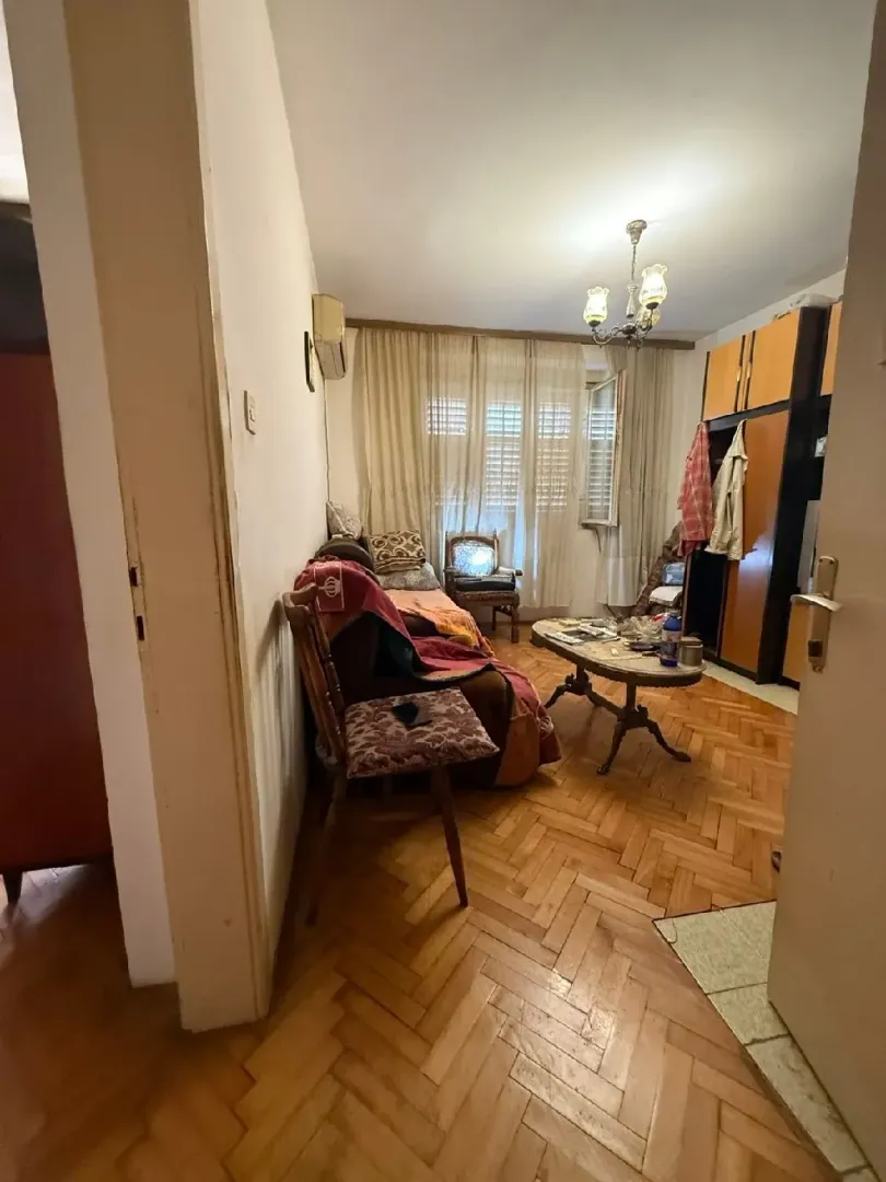 Pogled na stariji dnevni boravak sa parketom i namještajem.